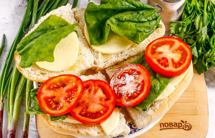 1. Этап. Панини с помидорами и моцареллой: Помидоры промойте в воде, вырежьте из них зеленые сердцевинки и нарежьте кружочками. Выложите на шпинат только на два кусочка хлеба.