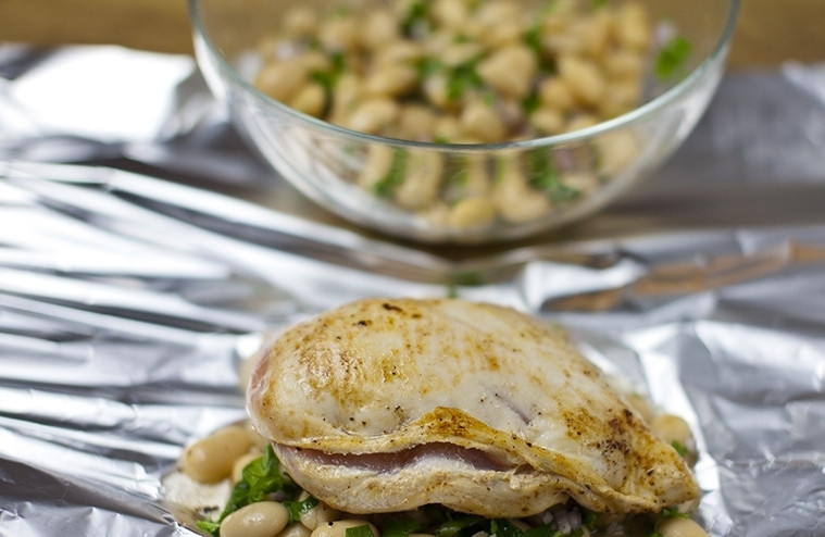 1. Этап. Грудка с фасолью: Теперь в середину листа фольги выкладываем 1/4 часть фасоли, а наверх кладем фаршированную грудку. Посыпаем ее острой паприкой и заворачиваем фольгу конвертиком.