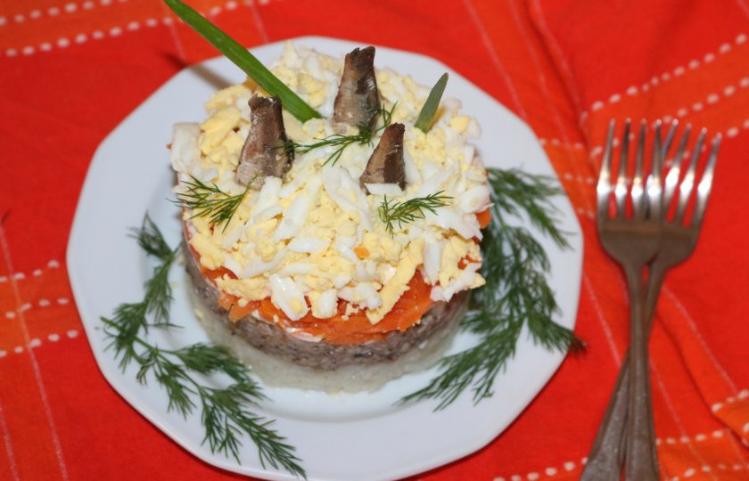 1. Этап. Салат из риса и шпрот: Украсьте салат зеленью и шпротными хвостиками.