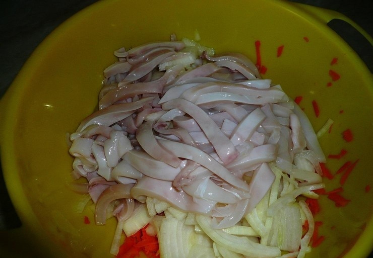 1. Этап. Кальмары с луком: Затем к овощам добавьте нарезанного соломкой кальмара. Ингредиенты перемешайте вместе с солью и маслом.