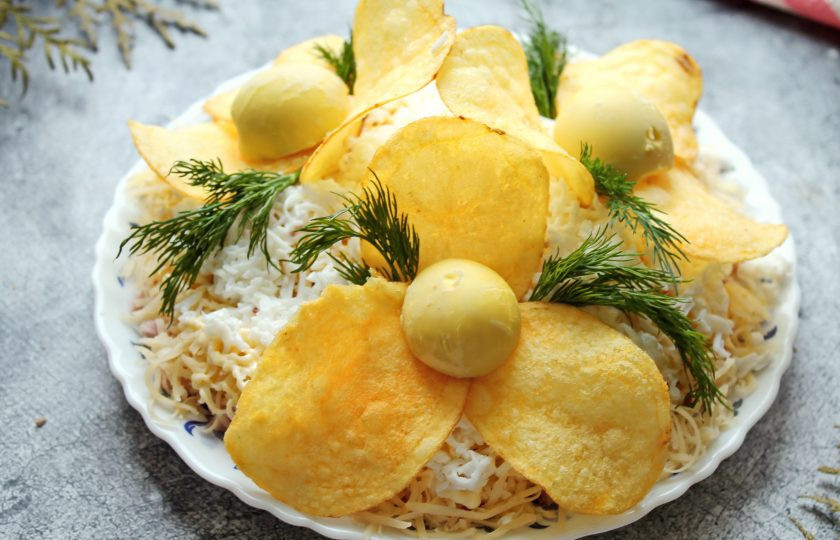 1. Этап. Салат Орхидея с чипсами и ветчиной: Из отложенных чипсов сделайте цветок орхидеи по три штуки на цветок. В середину нанесите немного майонеза и установите половинку желтка. Из укропа сделайте листики.