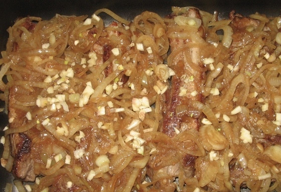 1. Этап. Ребрышки в медово-соевом соусе: В форму с тефлоновым покрытием выкладываем сначала рёбрышки, затем на них — обжаренный лук и измельчённый чеснок.