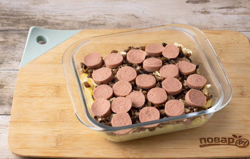 1. Этап. Картофельная запеканка с сосисками и грибами: Добавьте тертый сыр, сосиски и грибы.