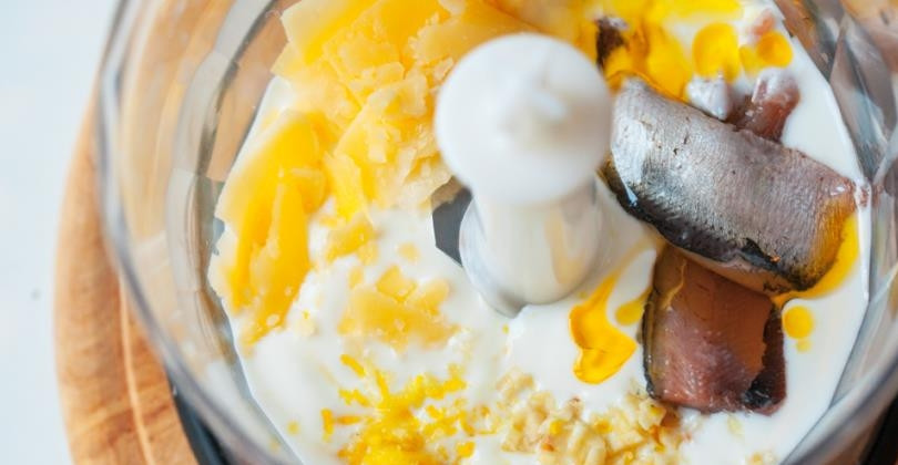 1. Этап. Соус к салату Цезарь: В чаше блендера смешайте йогурт, измельченный чеснок, цедру лимона, лимонный сок и анчоусы. Взбейте до однородной массы.