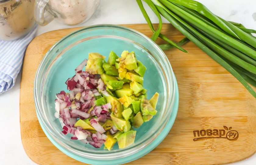 1. Этап. Брускетта с гуакамоле и креветками: Очистите красную луковицу от кожуры, промойте и разрежьте пополам. Нарежьте половину корнеплода мелким кубиком. Очистите половину авокадо от кожуры, нарежьте мякоть таким же мелким кубиком. Высыпьте обе нарезки в пиалу или миску.