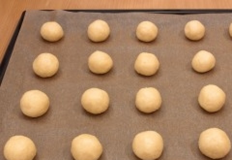 1. Этап. Выпечка из кокосовой стружки: 5. Подготовьте противень для выпекания: застелите пекарской бумагой, смажьте маслом. Сформируйте из теста шарики. Разложите их на противне и отправьте выпекаться на 20 минут, при температуре 180 С.