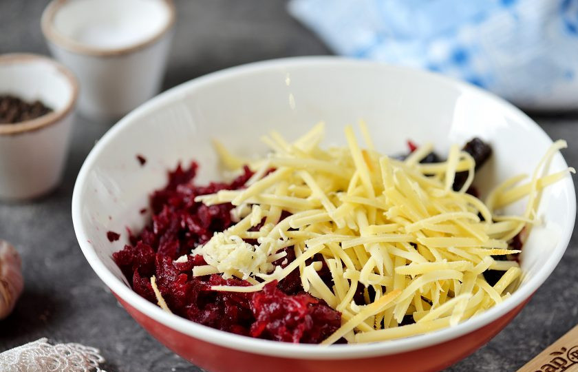 1. Этап. Салат из свеклы с черносливом и сыром: Натрите свеклу на крупной терке, переложите в миску к черносливу, добавьте твердый сыр. Зубчик чеснока почистите от шелухи, натрите на мелкой терке или пропустите через чесночницу.