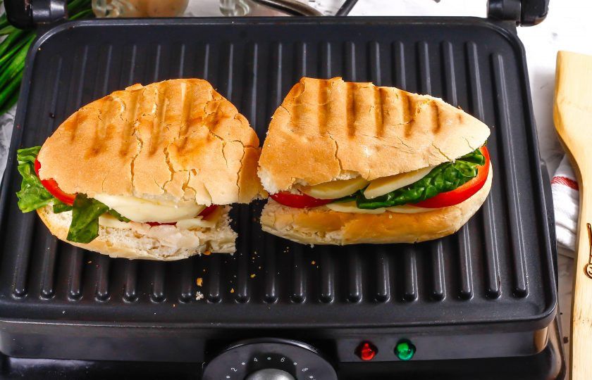 1. Этап. Панини с помидорами и моцареллой: Прогрейте электрогриль и выложите на него заготовки бутербродов. Аккуратно прикройте второй частью техники и зажарьте примерно 2 минуты, чтобы моцарелла стала мягкой.