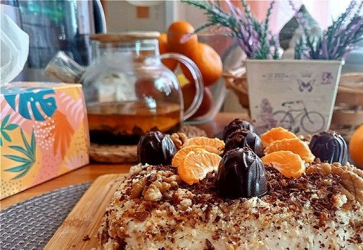 1. Этап. Пряничный торт: Время приготовления торта даю без выдержки в холодильнике. Его лучше делать на ночь, чтобы все пряники пропитались кремом творожным. Из общей массы оставляем 2 пряника. Они нам нужны для украшения торта. Берём форму любую. Моя квадратная со сторонами 20Х20 см и высотой 5 см. Застилаем её пищевой плёнкой. Пряники нужно разрезать пополам вдоль. Если они очень толстые, то разрежьте на 3 части. Я разрезала на 2. Делаем крем. Так как творог у меня из ванночек, то он мягкий без крупинок и блендер нам не понадобится. Я творог выбрала со вкусом ананаса и банана. Дольки этих фруктов в твороге небольшими фрагментами. Выкладываем его в посуду и добавляем сгущёнку. Пробуйте на вкус и сладость. Может меньше или больше уйти сгущёнки. Соединяем силиконовой лопаткой. Готов! Выкладываем на низ формы крем примерно толщиной 1-1,5 см. Раскладываем на него порезанные пряники. Берём половинку пряника и режем её на маленькие кусочки, чтобы заполнить пустые места. Сверху выкладываем ещё слой крема. На него - второй слой порезанных пряников. Порезанные пряники останутся. Второй слой промазываем всем оставшимся кремом. Теперь оставшиеся пряники измельчаем в крошку. Присыпаем ими крем, плотно утрамбовывая лопаткой. Утрамбовывайте плотно. Это будет основа торта. Всё. Подворачиваем края плёнки, накрываем крышкой и ставим в холодильник. Минимум торту нужно постоять 3 часа, чтобы он стабилизировался. Вынимаем, раскрываем края плёнки, выкладываем на блюдо, перевернув. Снимаем плёнку. Верх торта у нас кремовый. Два пряника, которые мы оставили целыми, сразу измельчаем в крошку и аккуратно присыпаем верх кремовый, можно - и бочка торта. Украшаем на свой вкус. Я пряничную крошку соединила с порубленными грецкими орехами 2 шт. А ещё 2 разложила половинками по краям торта. Прямо над тортом потёрла сверху горький шоколад. Выложила конфеты и добавила мелкие дольки мандарина. Торт готов к подаче.