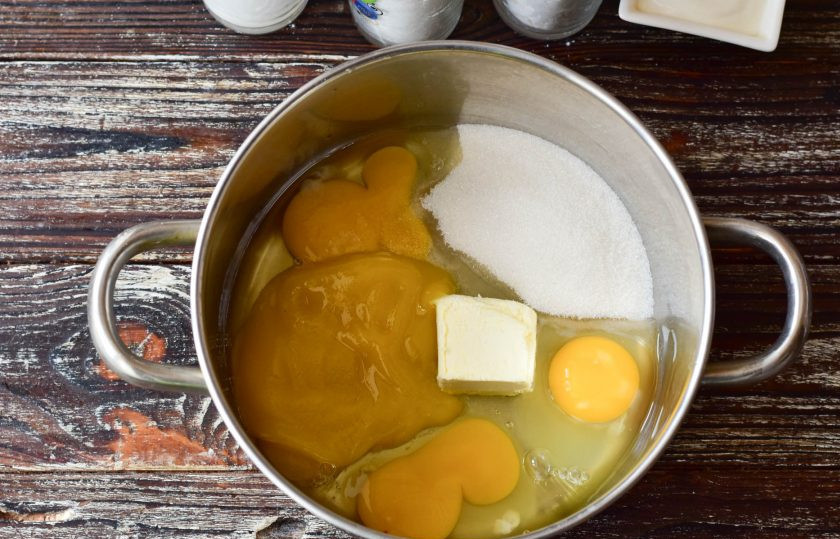 1. Этап. Медовик с орехами: В кастрюлю вбейте куриные яйца, всыпьте сахар и соль, выложите мед и сливочное масло.