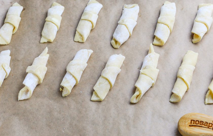 1. Этап. Рогалики песочные с орехами: Разогрейте духовку до 180 градусов и выложите заготовки на пергаментную бумагу на противень.