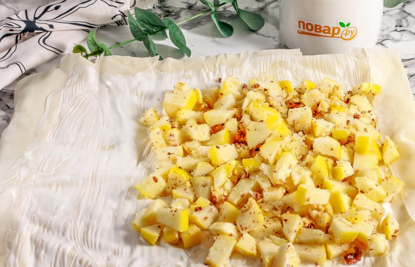 1. Этап. Рулет с яблоком и орехами: Разверните листы теста на доске или рабочей поверхности. Разогрейте духовку до 180 градусов. Смажьте верхний лист теста половиной сметаны. На одну часть теста выложите яблочно-ореховую начинку.