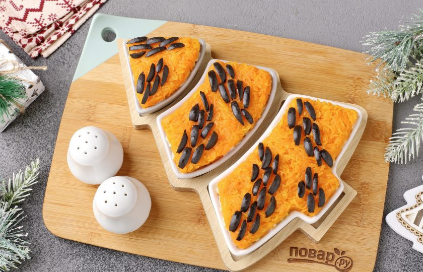 1. Этап. Салат Тигровая ёлочка: Морковь натрите на мелкой тёрке, слегка посолите и выложите сверху. Маслины нарежьте полосками и украсьте в виде гирлянды, напоминающей тигровую окраску.