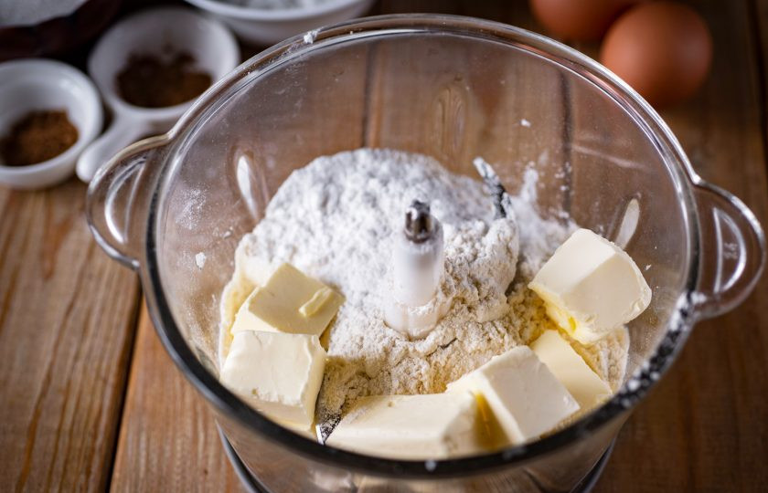 1. Этап. Тыквенный пирог классический: Пока варится пюре, приготовьте песочное тесто. В чашу измельчителя выложите всю муку, добавьте сахарную пудру, соль, холодное сливочное масло, нарезанное кубиками.