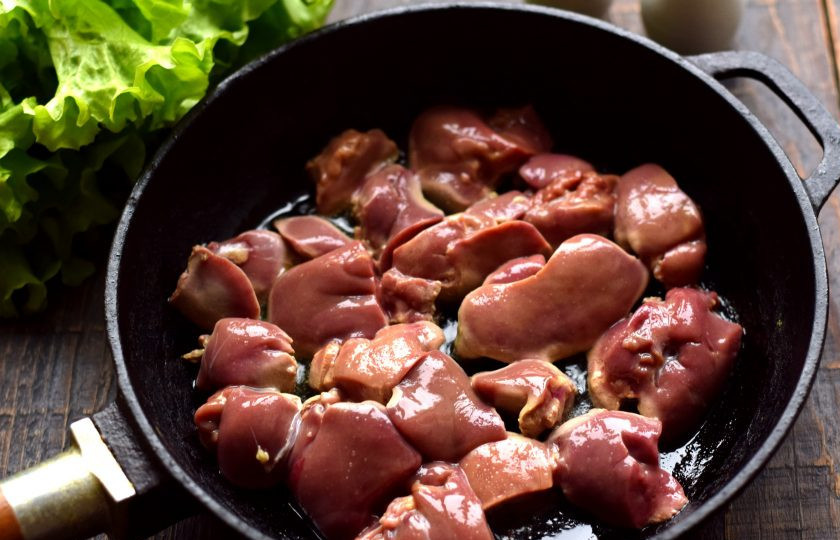 1. Этап. Салат с печенью и сухариками: Куриную печень ополосните, срежьте жировые прослойки и возможные сгустки крови. Разрежьте каждую печень на 2 или 4 части. Не нарезайте очень мелко, кусочки должны быть крупными или средними. Сковороду хорошо разогрейте, влейте небольшое количество оливкового масла. В горячее масло опустите печень.