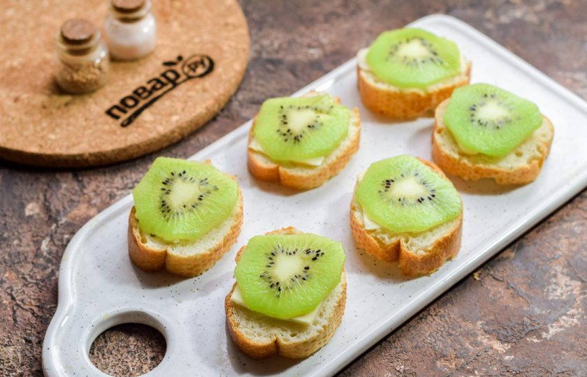 1. Этап. Бутерброды с селедкой и киви: Киви очистите и сполосните, нарежьте кружочками. Выложите каждый кусочек киви поверх батона.