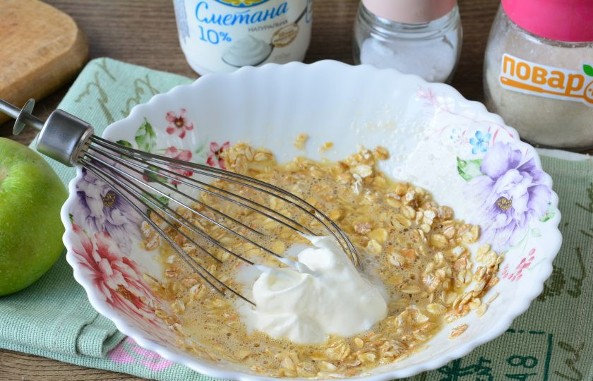 1. Этап. Творожная запеканка с геркулесом и яблоками: Добавьте геркулес, сметану и размешайте, оставьте массу на 15 минут, пусть геркулес набухнет.