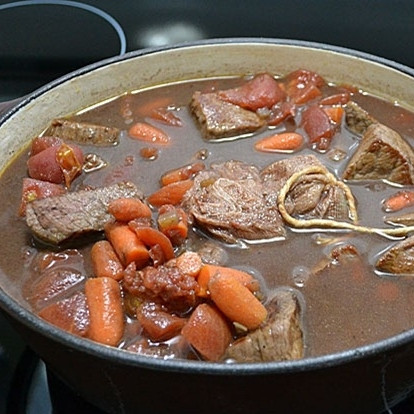 1. Этап. Говядина по-бургундски: Добавляем мелкими кубиками нарезанные помидоры и букет зелени, связанный ниткой или завернутый в марлю.