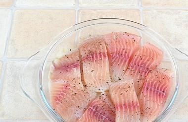 1. Этап. Рыба с луком и морковью: В форму для запекания в один слой выложите рыбу, порезанную порционными кусочками, немного посолите и поперчите.