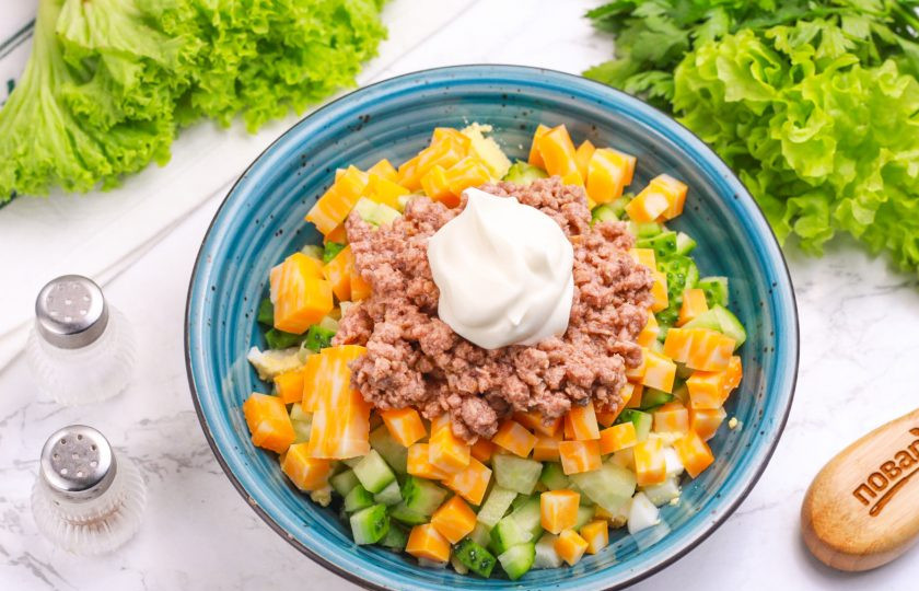 1. Этап. Салат с огурцом, сыром и тунцом: Добавьте майонез любой жирности, посолите. По желанию всыпьте и молотый черный перец. Аккуратно все перемешайте.