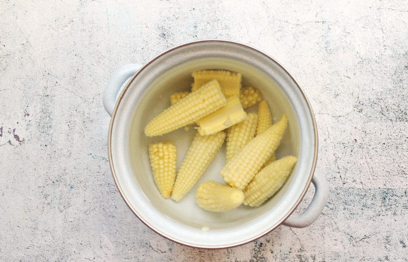 1. Этап. Мини-кукуруза в банке на зиму: В кастрюлю налейте один литр воды, добавьте 10 грамм соли и 2 грамма лимонной кислоты, доведите до кипения. Выложите початки мини-кукурузы и варите в течение 15 минут. Переложите кукурузу в холодную соленую воду, на 1 литр воды 10 грамм соли, и дайте остыть.