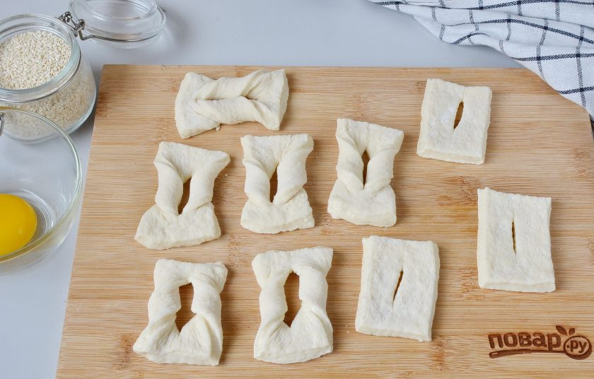 1. Этап. Пышки в духовке: Раскатайте тесто, толщина 5-6 мм., порежьте небольшими прямоугольниками, в центре каждого сделайте надрез и через него выверните один край.