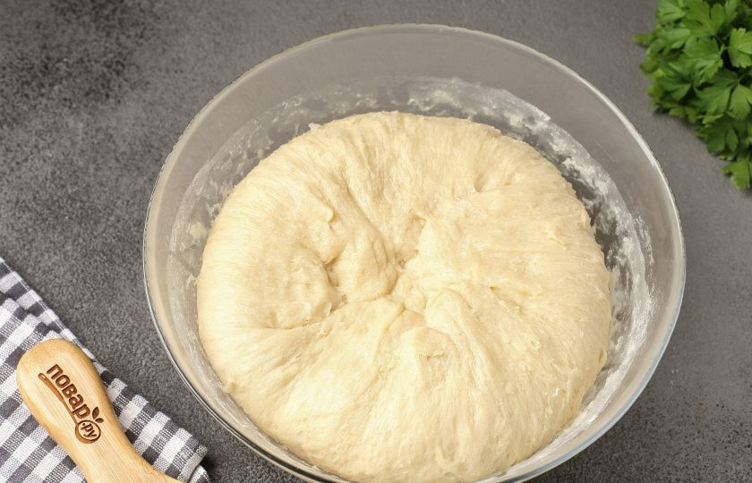 1. Этап. Дрожжевое тесто на подсолнечном масле для печёных пирожков: Тесто обминаем и вновь накрываем пищевой плёнкой.