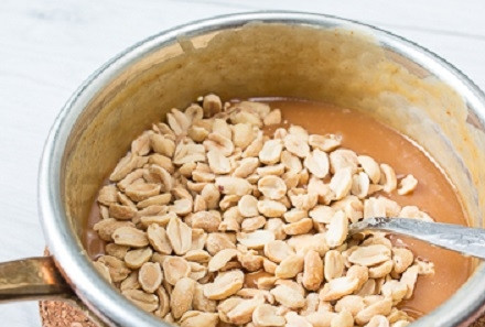 1. Этап. Сникерс в домашних условиях: Обжаренный арахис добавляем в карамель и размешиваем.