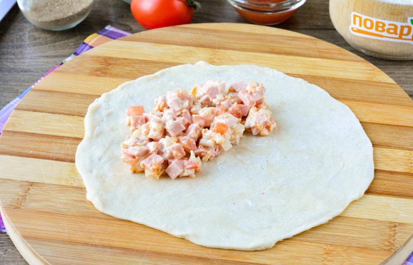 1. Этап. Пицца в чебуреке: Отдохнувшее тесто разделите на равные части, каждую тонко раскатайте, придавая круглую форму. Выложите на половину заготовки начинку — 1-2 ст. л.