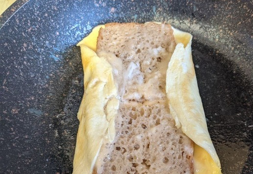 1. Этап. Омлетный сэндвич с индейкой: Даём омлету схватиться. Убавляем огонь до минимума, чтобы омлет не сгорел, пока будем с ним делать манипуляции. Заворачиваем края омлета с обеих сторон на хлеб.