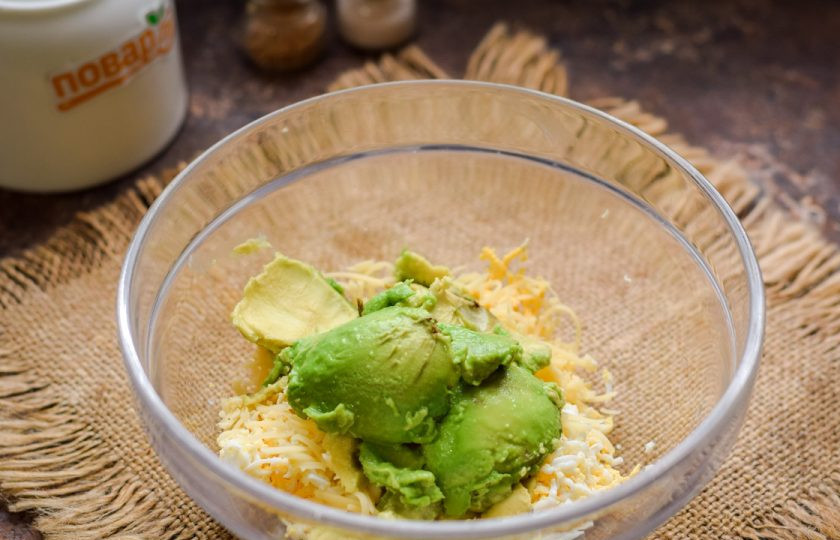 1. Этап. Авокадо фаршированное креветками: Авокадо разрежьте, извлеките мякоть плода и переложите в миску к яйцам и сыру.