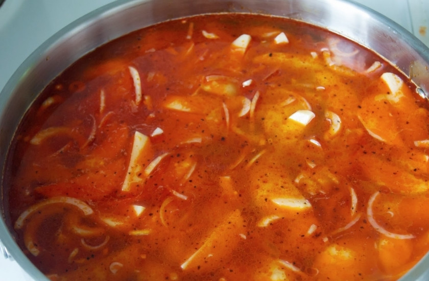 1. Этап. Рыба тушеная с картофелем: В сотейник для тушения выкладываем нарезанный дольками картофель, лук, оставшийся чеснок. Заливаем оливковым маслом и смесью с вином. Добавляем воды, чтоб покрывало все кусочки. Солим, перчим, доводим до кипения, варим минут 10.