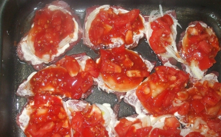 1. Этап. Говядина кусочками в духовке: Мелко нарежьте помидоры и смешайте с томатной пастой и измельченным чесноком. Перемешайте и выложите полученную массу на мясо.