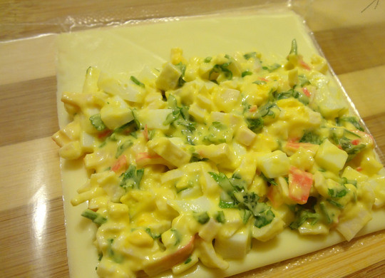 1. Этап. Плавленый сыр с начинкой: Выкладываем на сырный пластик немного начинки и разравниваем ее на 2/3 поверхности ломтика.