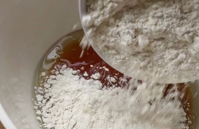 1. Этап. Лунные кексики: 1. Начните приготовление кексиков со смешивания теста. В одной миске взбейте мед, масло и воду. После добавьте муку и тщательно вымешивайте до однородности.