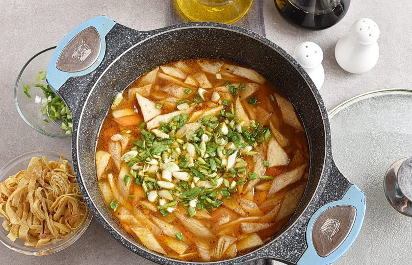 1. Этап. Корейский суп: Посыпьте суп большей частью зеленого лука и размешайте.