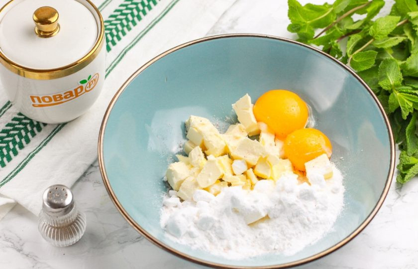 1. Этап. Домашнее печенье: Нарежьте сливочное масло в глубокую емкость кубиками или кусочками. Всыпьте соль и сахарную пудру, добавьте желтки куриных яиц. Лучше всего использовать пудру, чтобы крупинки сахара не попадались в тесте. Тщательно разотрите все между собой.