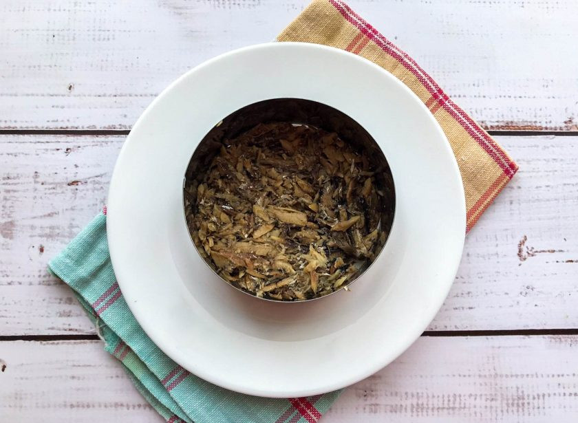 1. Этап. Салат со свеклой и шпротами: На тарелку поставьте сервировочное кольцо. На дно тарелки выложите шпроты, предварительно размяв их вилкой.