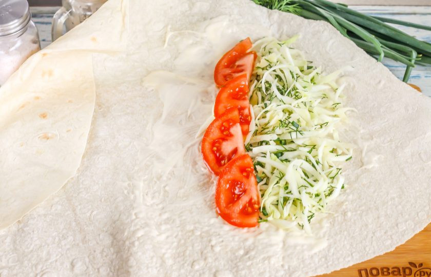 1. Этап. Денеры в лаваше: Промойте помидор и нарежьте его полукольцами, вырезая зеленую сердцевину. Выложите на капусту.