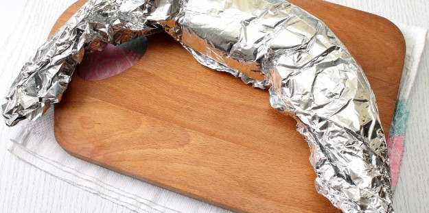 1. Этап. Рыба по-уральски: Тщательно заверните щуку в фольгу, чтобы в процессе запекания не вытекал выделившийся сок. Лучше, если вы будете заворачивать рыбу в несколько слоев фольги.