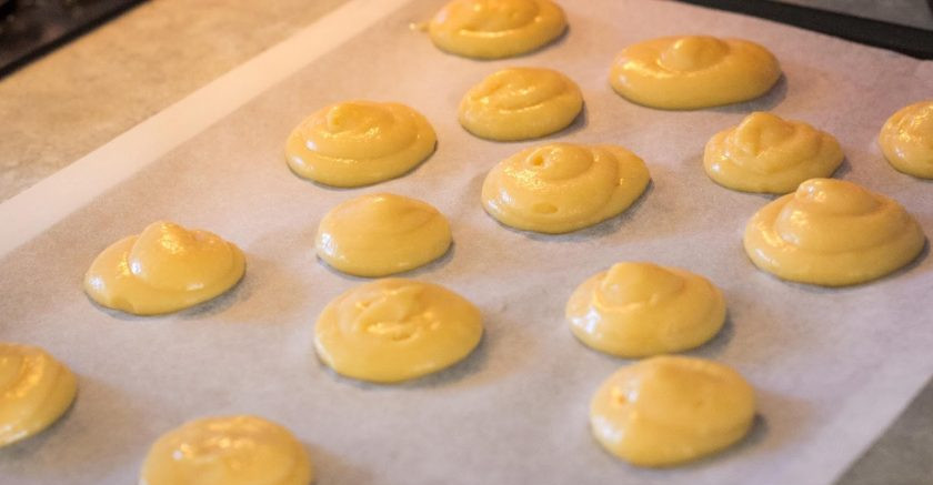 1. Этап. Профитроли с творожным кремом: Поместите тесто в кондитерский мешок с большой насадкой. Отсадите профитроли на противень, застеленный пергаментной бумагой.