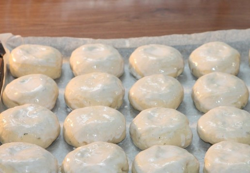 1. Этап. Круглые пирожки с овощами и яйцом: 13. Застилаем противень пекарской бумагой и смазываем маслом. Раскладываем заготовки пирожков и смазываем жидкой сметаной. Ставим противень в теплое место до увеличения пирожков в 2 раза, минут на 20.