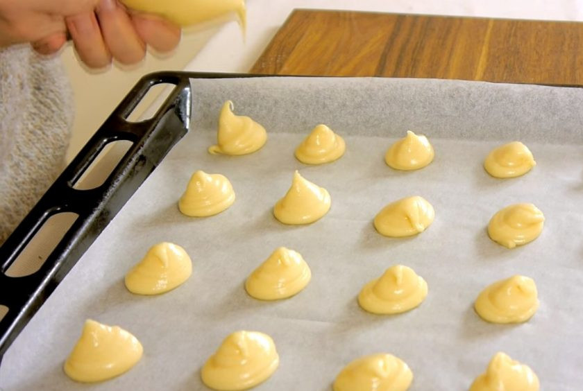 1. Этап. Профитроли закусочные: 3. Переложите тесто в пакет, срежьте угол пакета и высадите профитроли размером с грецкий орех на противень, застеленный бумагой для выпечки. Смоченным в воде пальцем подровняйте форму профитролей.