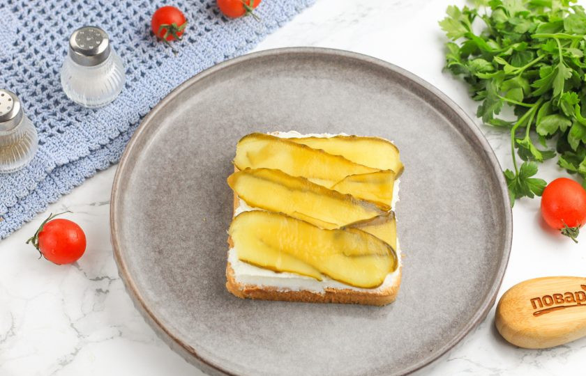 1. Этап. Канапе с семгой и икрой: С помощью овощечистки нарежьте соленый огурец и выложите ленты на творожный сыр.