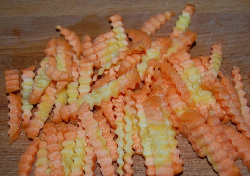 1. Этап. Тушеная картошка с тушенкой: Помойте и очистите морковь. Порежьте морковку небольшими брусками. В сковородку положите жир из тушенки. На него выложите морковь, обжарьте 5 минут.