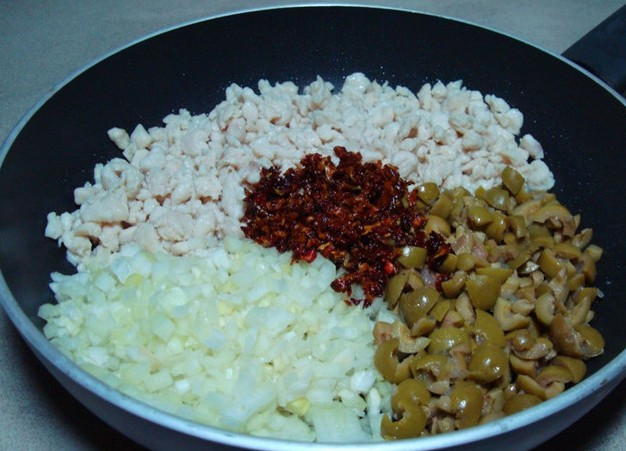 1. Этап. Пирожки с куриным фаршем: Добавляем измельченный лук и чеснок, оливки, нарезанные мелко помидоры. Солим и перчим по вкусу, жарим все вместе 5 минут.