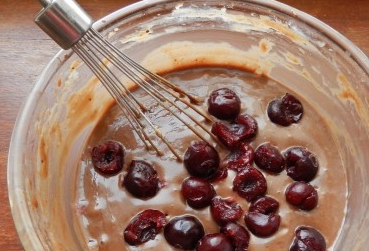 1. Этап. Кексики с вишней: Добавьте какао, растительное масло и вишню. Аккуратно перемешайте.