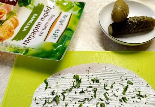 1. Этап. Закусочные роллы из ветчины с огурцом: Смазать сливочным сыром ветчину, посыпать нарезанной зеленью. Положить в середину маринованный огурец.