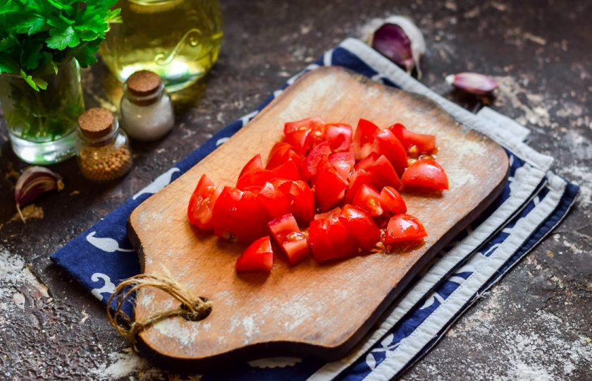 1. Этап. Салат Украинский на зиму: Помидоры нарежьте небольшими кубиками, место роста плодоножки удалите.