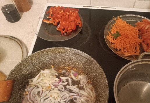 1. Этап. Яичная лапша с кальмаром и овощами: В разогретую сковородку с растительным маслом (вкуснее будет с оливковым, но кошка не пошла в магазин за ним) кладём чеснок и обжариваем буквально секунд 30-40. Следом добавляем лук и обжариваем до того момента, как лук станет прозрачнее. Одновременно с этими процессами ставим на плитку кастрюлю с подсоленной водой и следим вторым глазом как вода закипит.